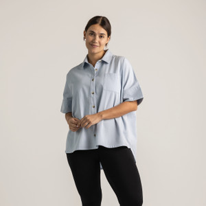 Close up front view of model wearing 100% organic cotton camp shirt in color light blue.