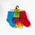 Red solid color, tie-dyed colorful, and bright blue solid color organic cotton baby anklet socks. Pack of three in yellow store packaging.