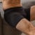 Close up lifestyle photo of model sitting wearing organic cotton essentials men's boxer brief 2 pak in color black.