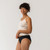 Close up side view of model wearing organic cotton essentials women's bikini 2 pak in color black.