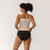 Close up back view of model wearing organic cotton essentials women's bikini 2 pak in color black.