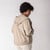 Back view of model wearing organic cotton hooded cardigan in putty.