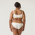 Close up back view of model wearing organic Cotton Women's Low-Rise Bikini in color natural.