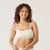 Front view of model wearing organic cotton strappy bralette in color natural.