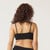 Back view of model wearing organic cotton strappy bralette in color black.