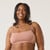 Front view of model wearing organic cotton strappy bralette in color clay.