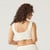Back view of model wearing organic cotton scoop bralette in color natural.