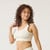 Front view of model wearing organic cotton scoop bralette in color natural.