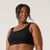 Front view of model wearing organic cotton scoop bralette in color black.
