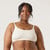 Front view of model wearing organic cotton ruched bralette in color natural.