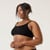 Side view of model wearing organic cotton ruched bralette in color black.