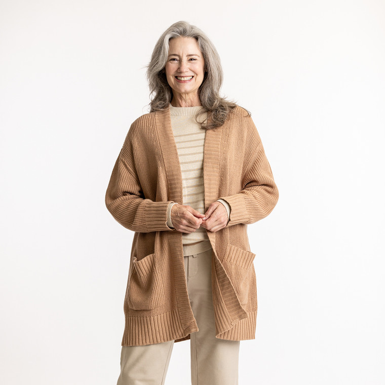 Front view of model with hands in pocket wearing organic cotton cardigan sweater in color turmeric