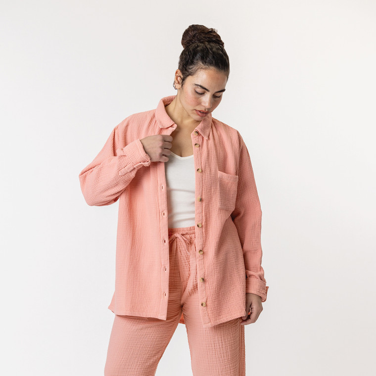 Close up front view of model wearing organic cotton button down shirt in color blush.