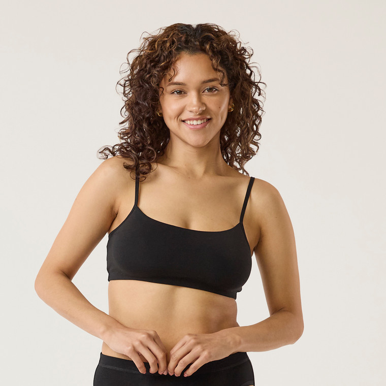 Front view of model wearing organic cotton strappy bralette in color black.