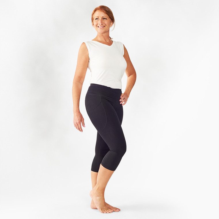 Model wearing black solid color organic cotton mid calf blackout leggings shown from the side.